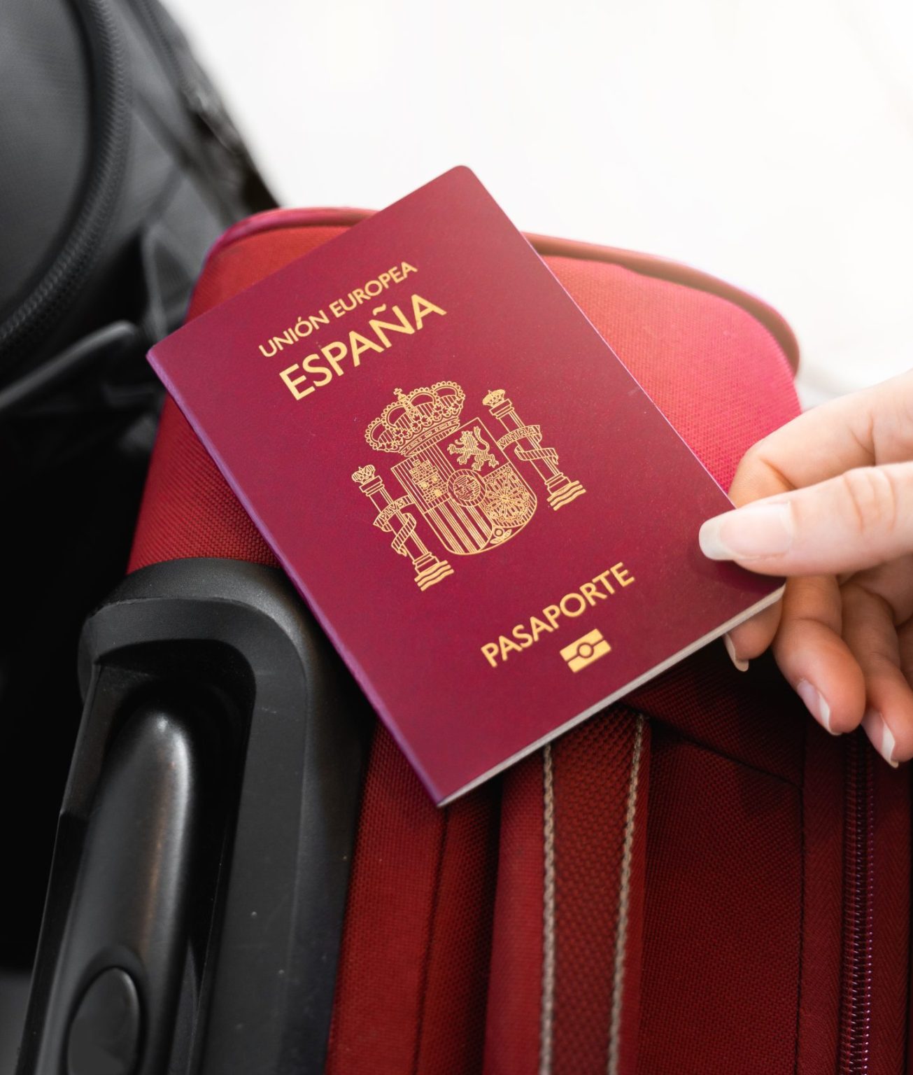 unrecognizable-female-hand-holds-a-spanish-european-passport-on-luggage